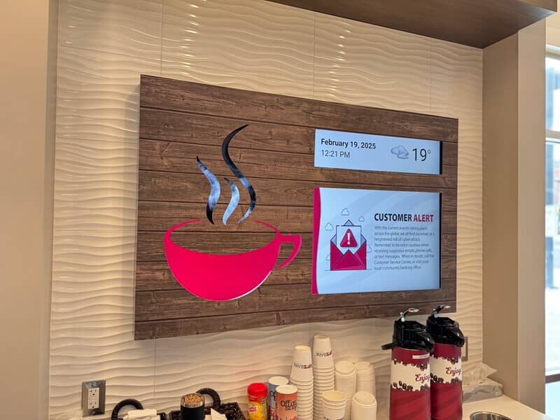 An image of interior signage for a coffee shop with a red mug against a wooden base.